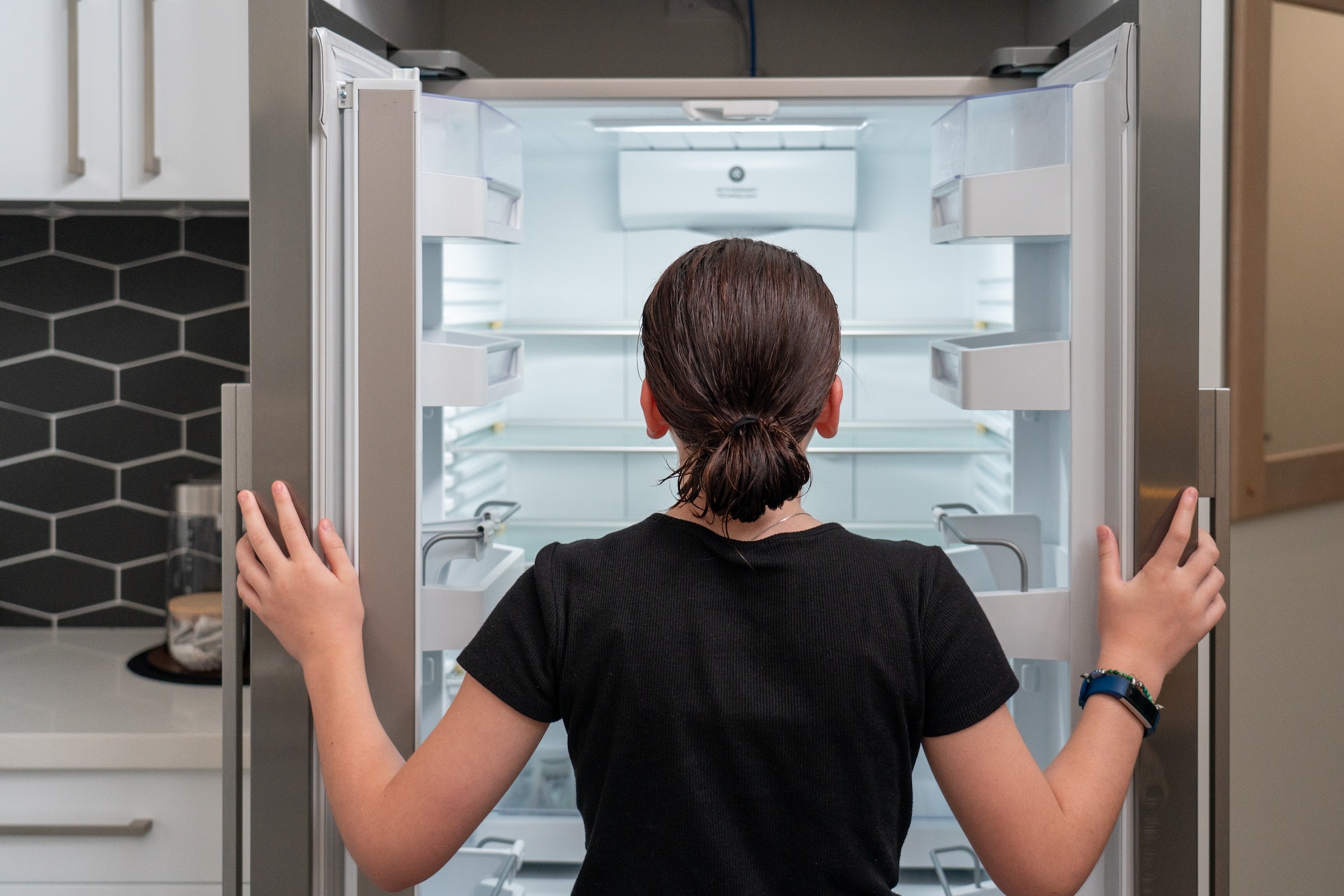 young girl looking into an empty Refrigerator fridge, Looking into empty fridge concept